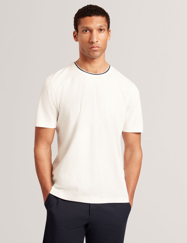 Man wearing a white t-shirt with a black trim on a gray background