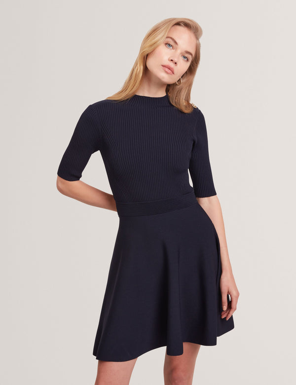 Woman wearing a navy blue dress with a plain background