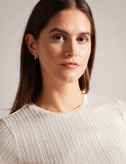 A woman wearing a gold ribbed t-shirt with metallic woven stripes and short sleeves.